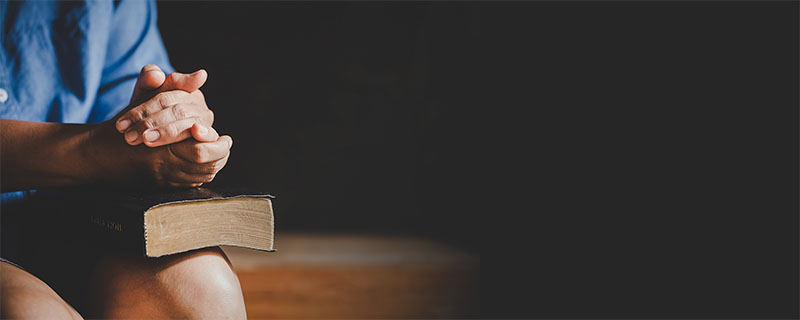 banner image of person praying over a bible